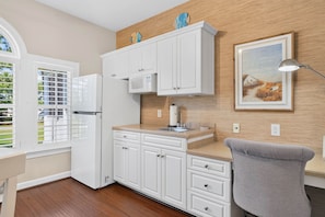 A modern kitchen with white cabinetry, a built-in microwave, and a wooden backsplash. - Easy Breezy on the 16th Green in Sunset Beach (Sunset Beach)