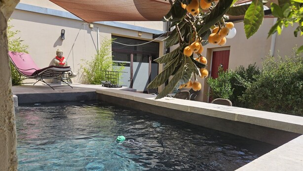 Una piscina con agua cristalina, rodeada por una terraza con una silla y una pequeña estatua.