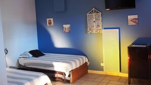 Un dormitorio con dos camas, un televisor y un mueble pequeño.