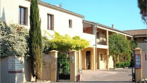 Un hotel con entrada protegida por un portón, varios balcones e indicación con información.