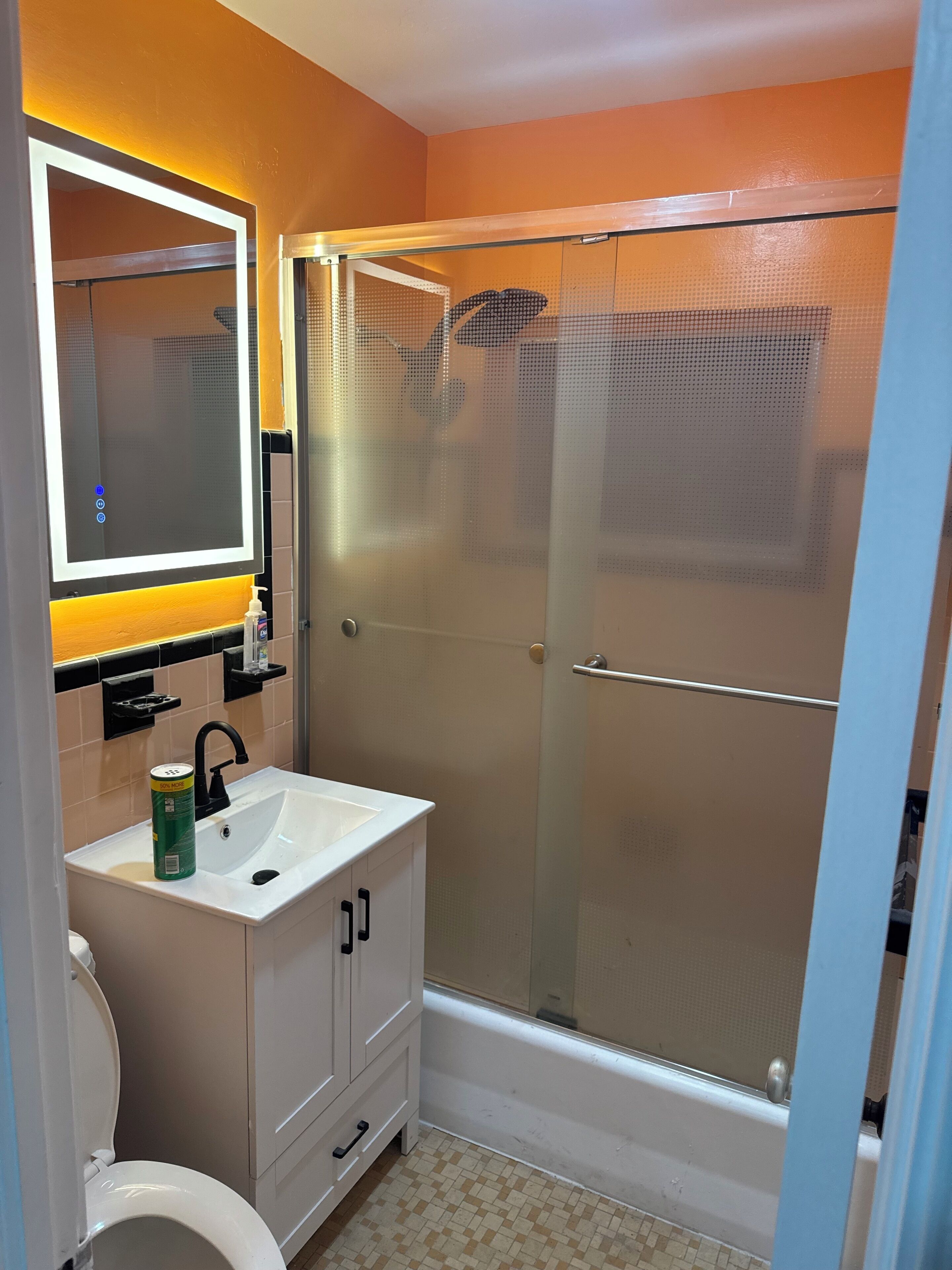 A bathroom with a white sink, a mirror, a toilet, and a glass-enclosed shower.