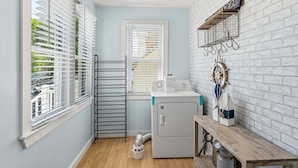 A laundry room with a washing machine, dryer, and a wooden bench.