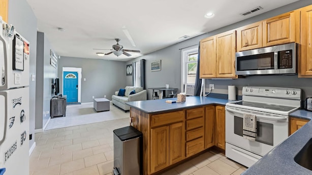 A modern kitchen with wooden cabinets, a built-in microwave, and a stainless steel refrigerator.