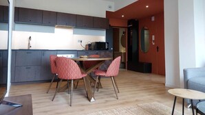 Una cocina moderna con armarios oscuros, una zona de comedor con sillas rojas de estampado y una mesa pequeña.