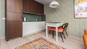 Una cocina moderna con armarios de madera, encimera blanca y un comedor con mesa y sillas.