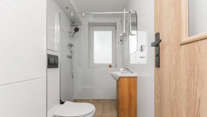 Un baño pequeño con inodoro, lavamanos y ducha.