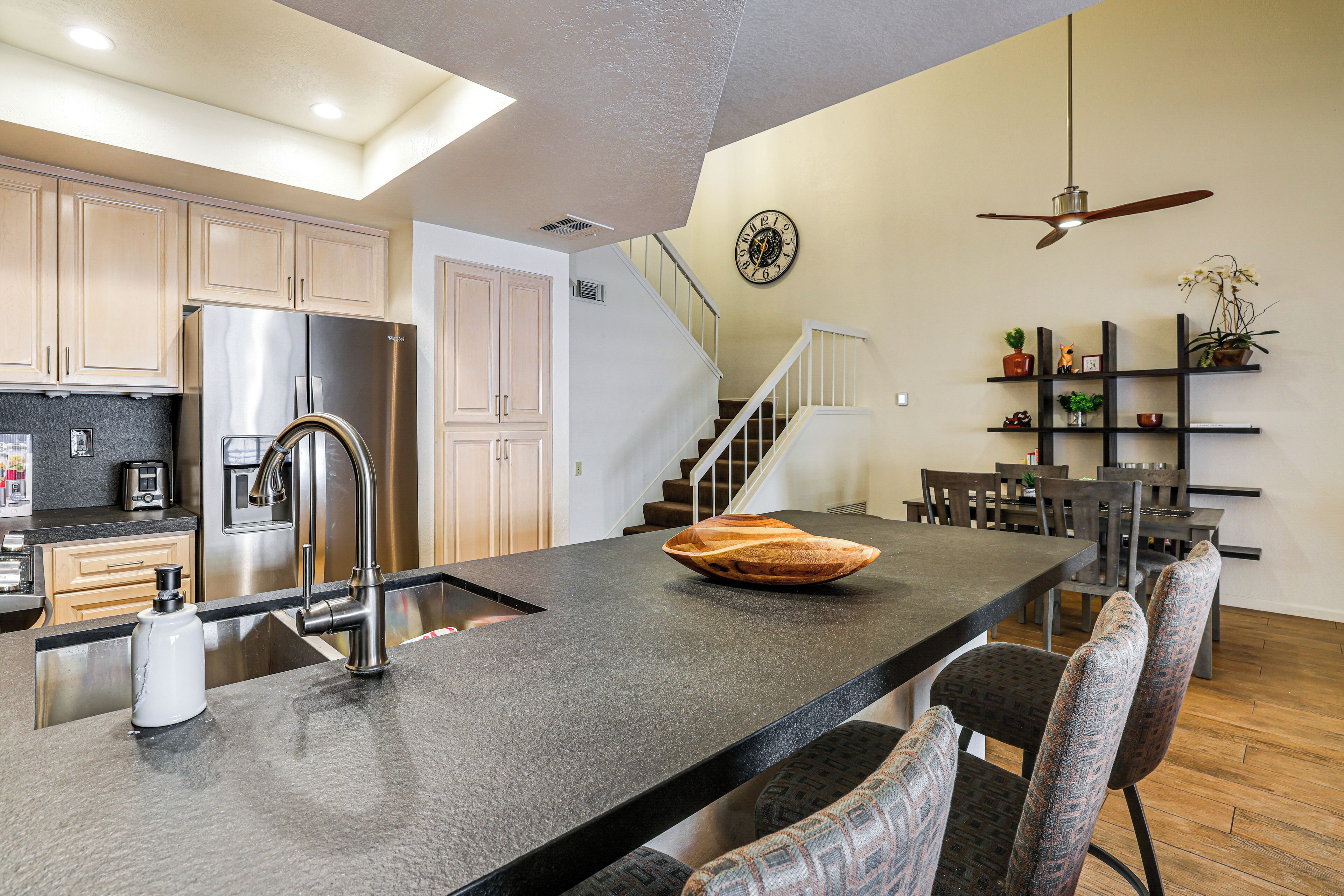 A modern kitchen with a central island, stainless steel appliances, and a dining area with chairs and a table.