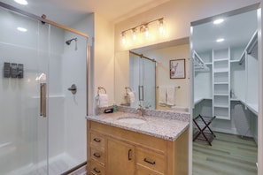 Un baño con ducha compartimentada con vidrio, tocador con lavamanos y un espejo grande.
