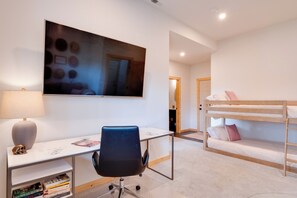 Un dormitorio con literas, un escritorio con silla, una lámpara y una estantería.