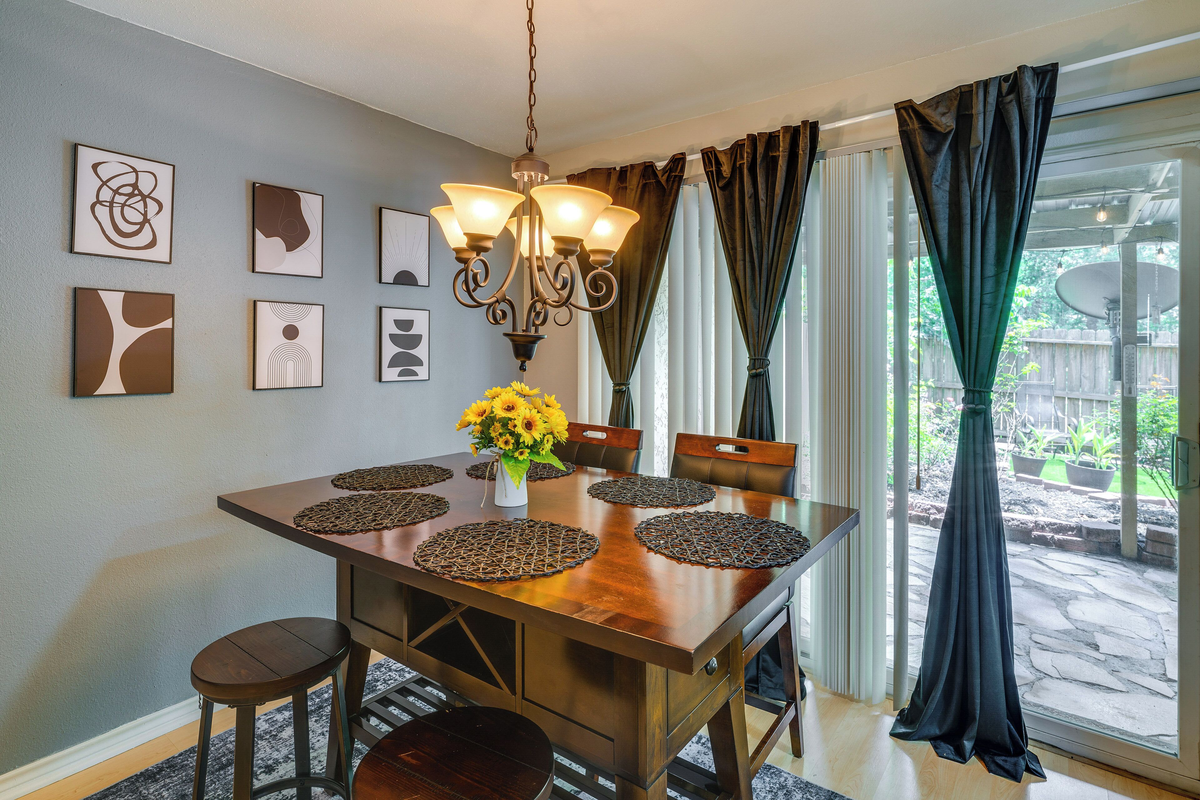 Un coin repas avec une table en bois, des chaises, un lustre et des œuvres d’art accrochées au mur.