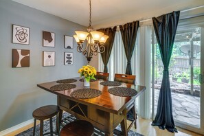 A dining area with a wooden table, chairs, a chandelier, and artwork on the wall. - Unit w/ Patio & Resort Perks! Walk to Lake Conroe (Montgomery)