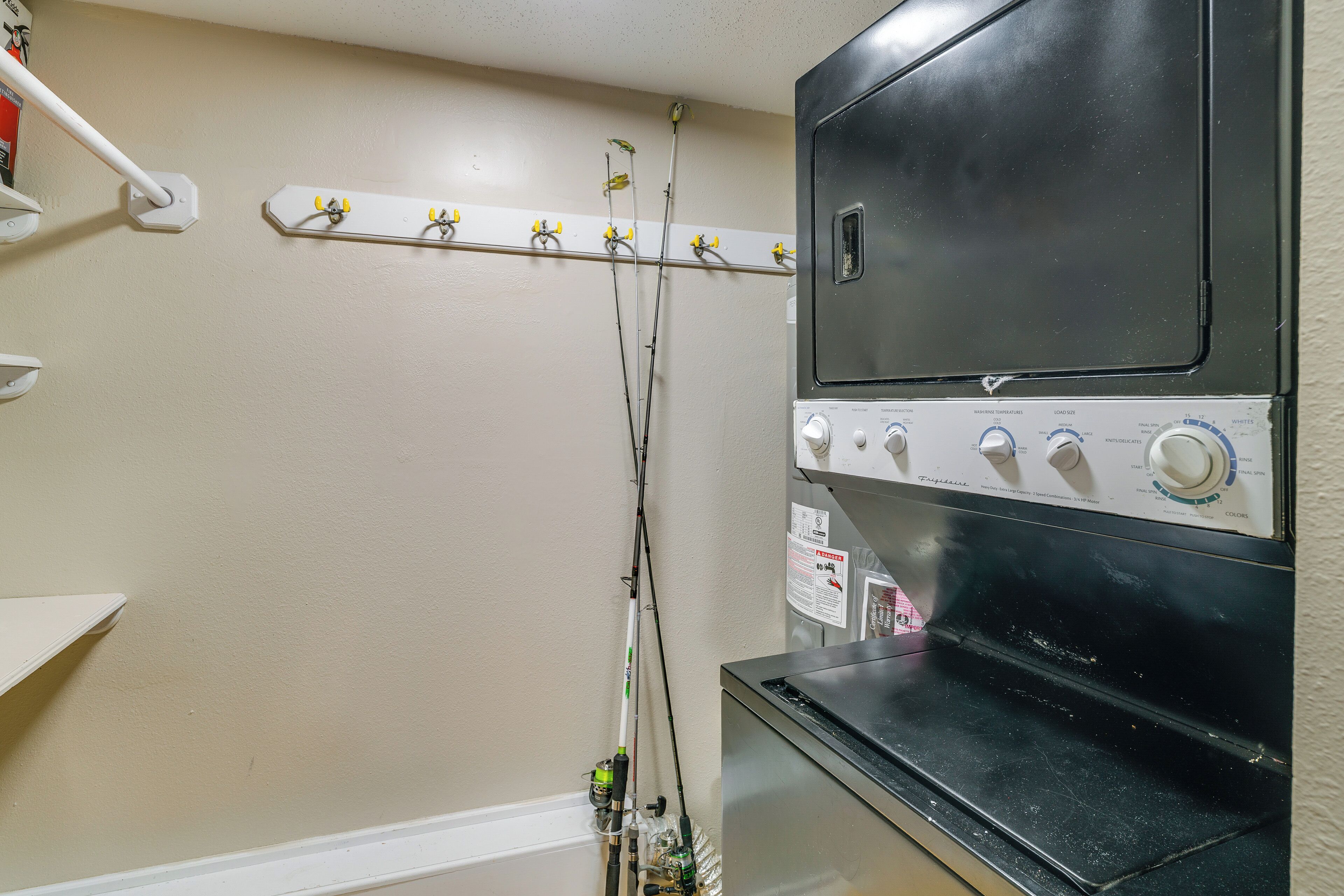 A laundry area with a washing machine, a drying rack, and a wall-mounted electrical outlet.
