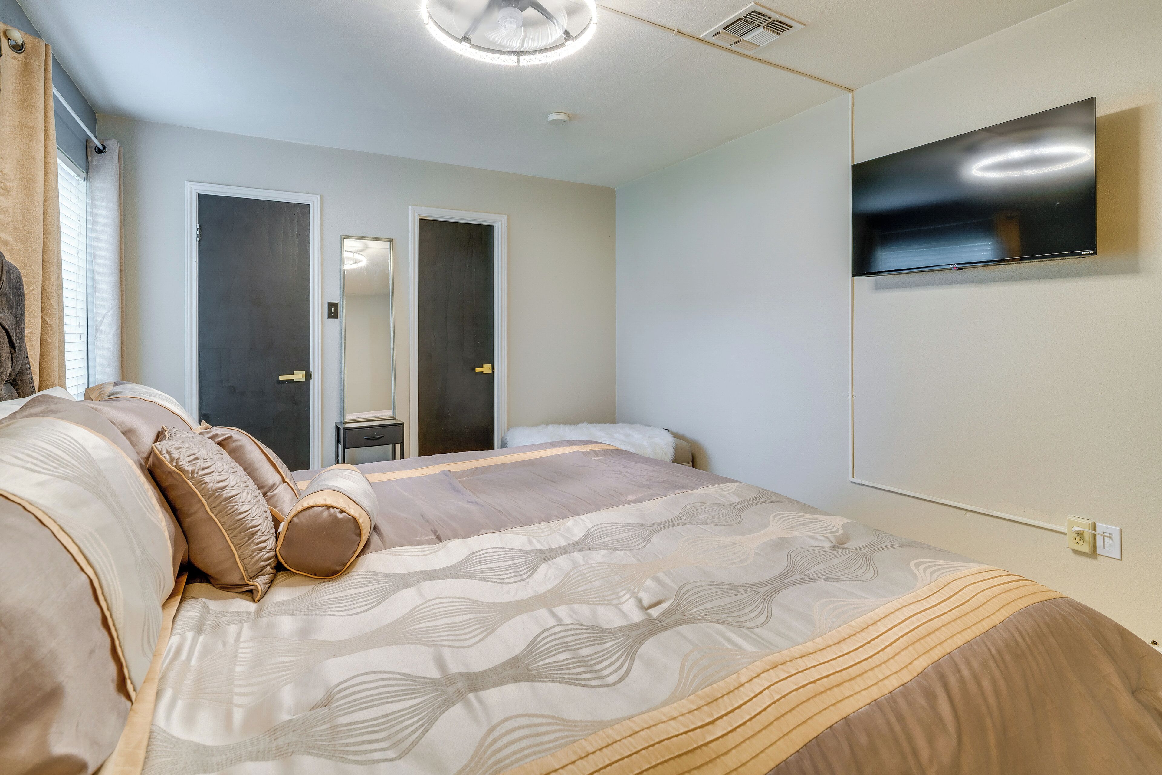 A bedroom with a bed, a TV mounted on the wall, and a door.