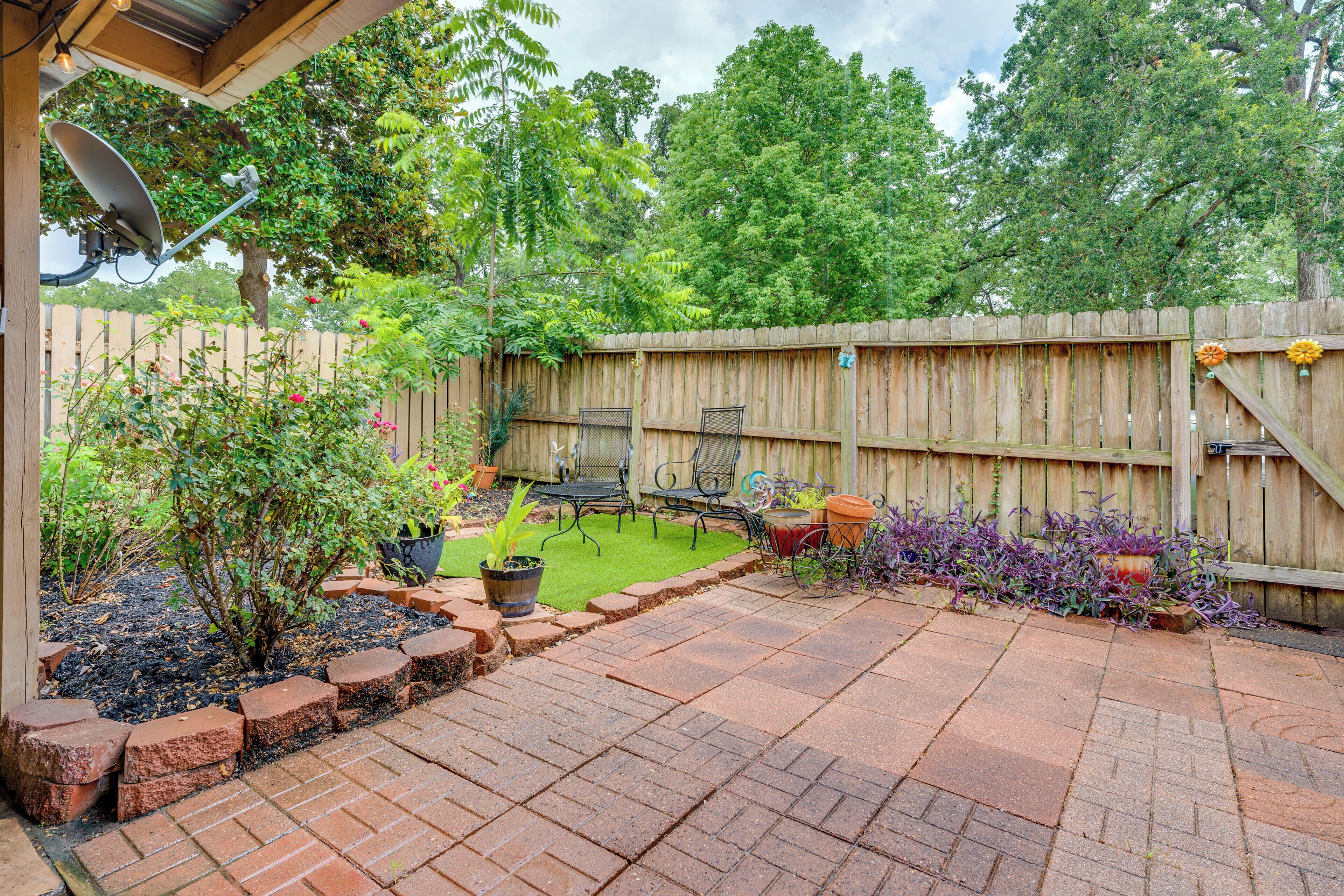 Un jardin avec une terrasse, une clôture en bois et du mobilier d’extérieur.
