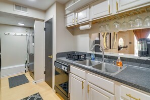 A kitchen with a dishwasher, double sink, and a countertop with a dish rack and a bottle of dish soap.