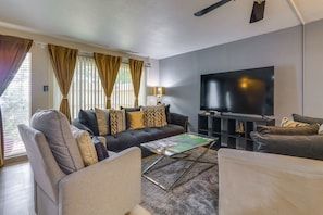 A living room with a sofa, armchairs, a coffee table, a flat-screen TV, and a bookshelf. - Unit w/ Patio & Resort Perks! Walk to Lake Conroe (Montgomery)
