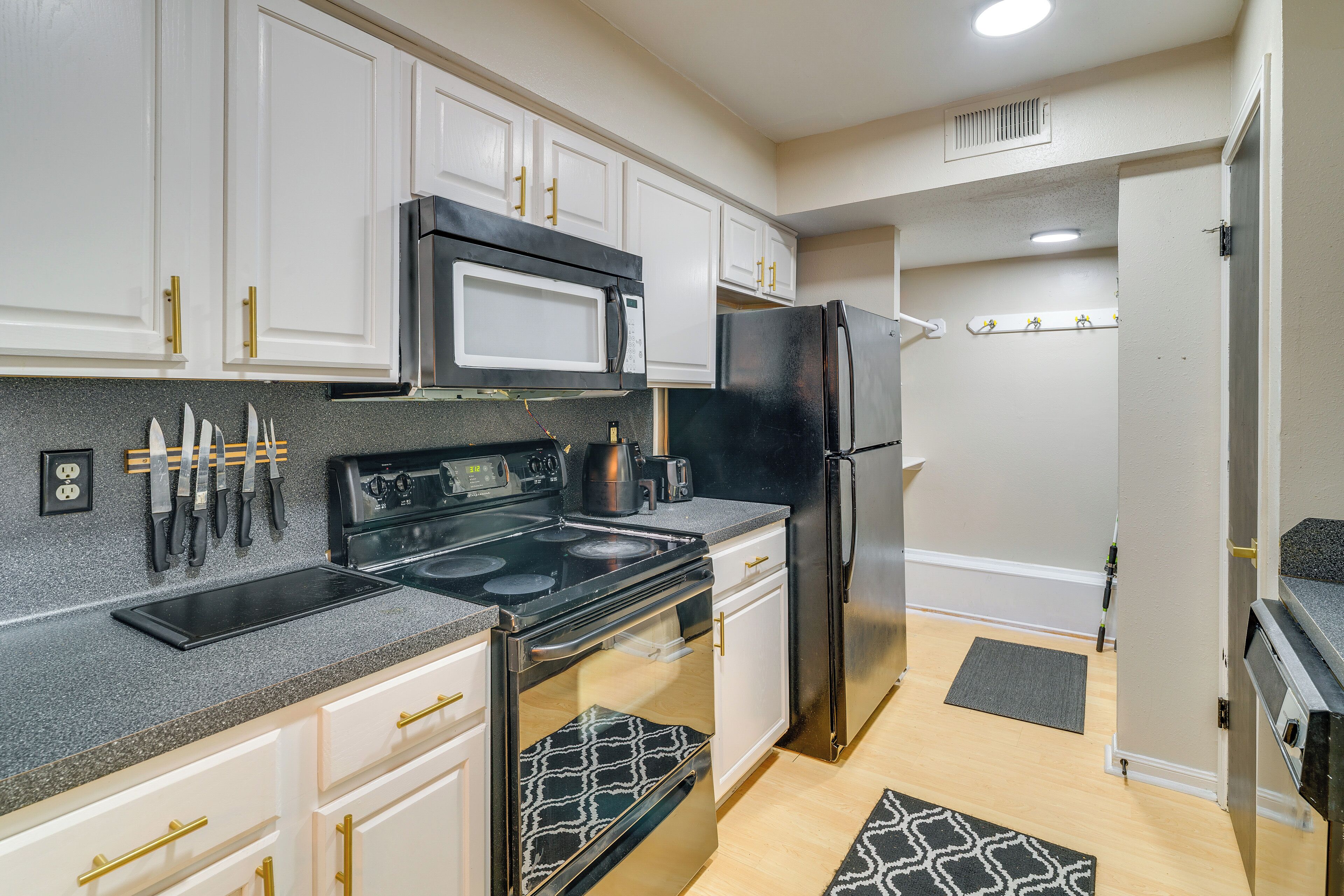 A kitchen with white cabinets, a black refrigerator, a microwave, and a stove.