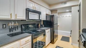 A kitchen with white cabinets, a black refrigerator, a microwave, and a stove.