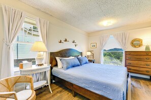 Un dormitorio con una cama de madera, un espejo redondo, un aparador y una ventana con cortinas.