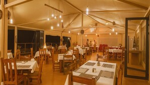 Un área de comedor con carpas, mesas y sillas, una zona de servicio y vistas al cielo nocturno.