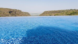 Una piscina infinita de color azul intenso con vistas a un paisaje montañoso.