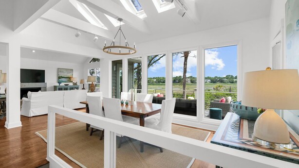 Een ruime woonkamer met een eethoek, grote ramen en uitzicht op het omliggende landschap.