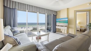 Ein Hotelzimmer mit Balkon, einer Sitzecke, einem Fernseher und Blick auf den Strand.