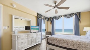 Ein Schlafzimmer mit einem Bett, einem Schminktisch, einem Fernseher und einem Deckenventilator.