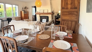 Een eetruimte met een houten tafel gedekt voor vier personen, een open haard en uitzicht op de omgeving.