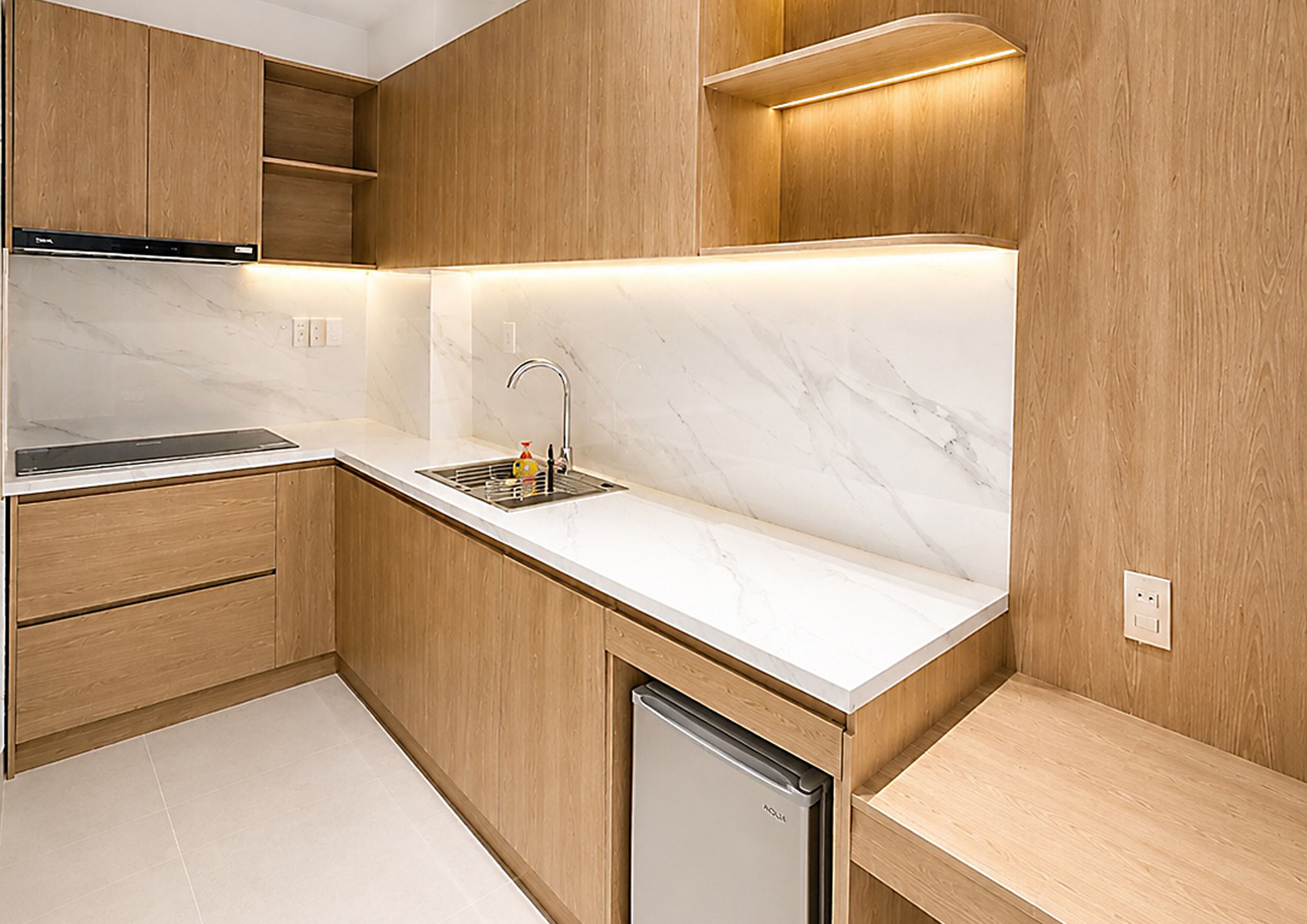 A modern kitchen with wooden cabinets, a marble countertop, and a built-in dishwasher.
