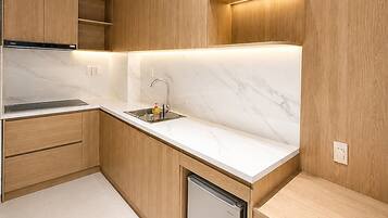 A modern kitchen with wooden cabinets, a marble countertop, and a built-in dishwasher.