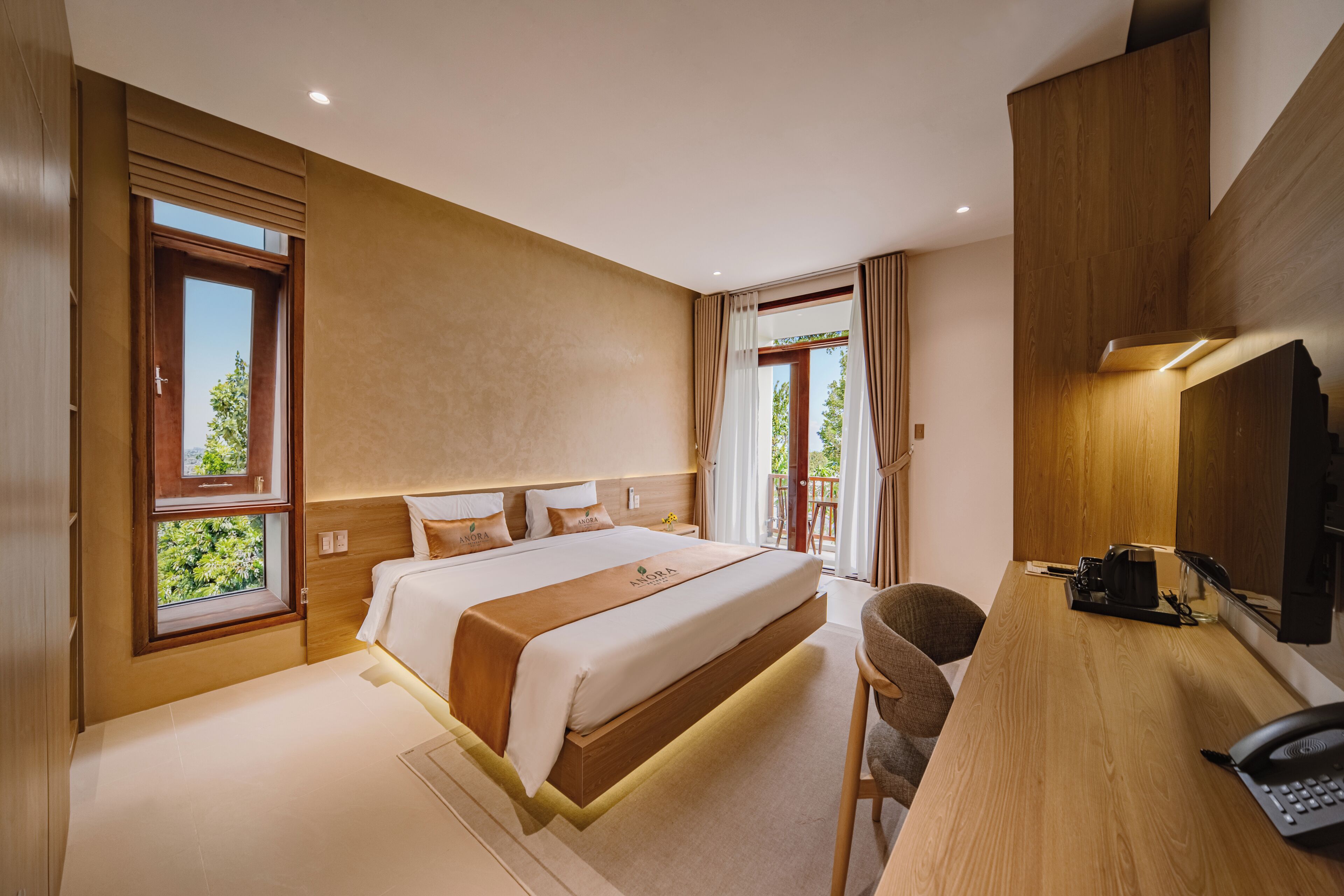 Habitación de hotel moderna con una cama grande, un escritorio con teléfono y vistas a zonas verdes.
