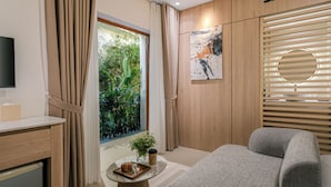 Una sala de estar moderna con un sofá, una mesita de centro con un croissant, una planta pequeña y un cuadro en la pared.