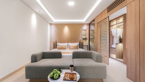 Une chambre moderne avec un canapé-lit, une table de chevet sur laquelle se trouvent des pommes et une tasse de café, et une armoire dans laquelle est suspendu un peignoir.