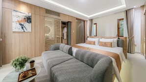 Una habitación de hotel moderna con cama, sofá y una mesita con planta y bandeja.