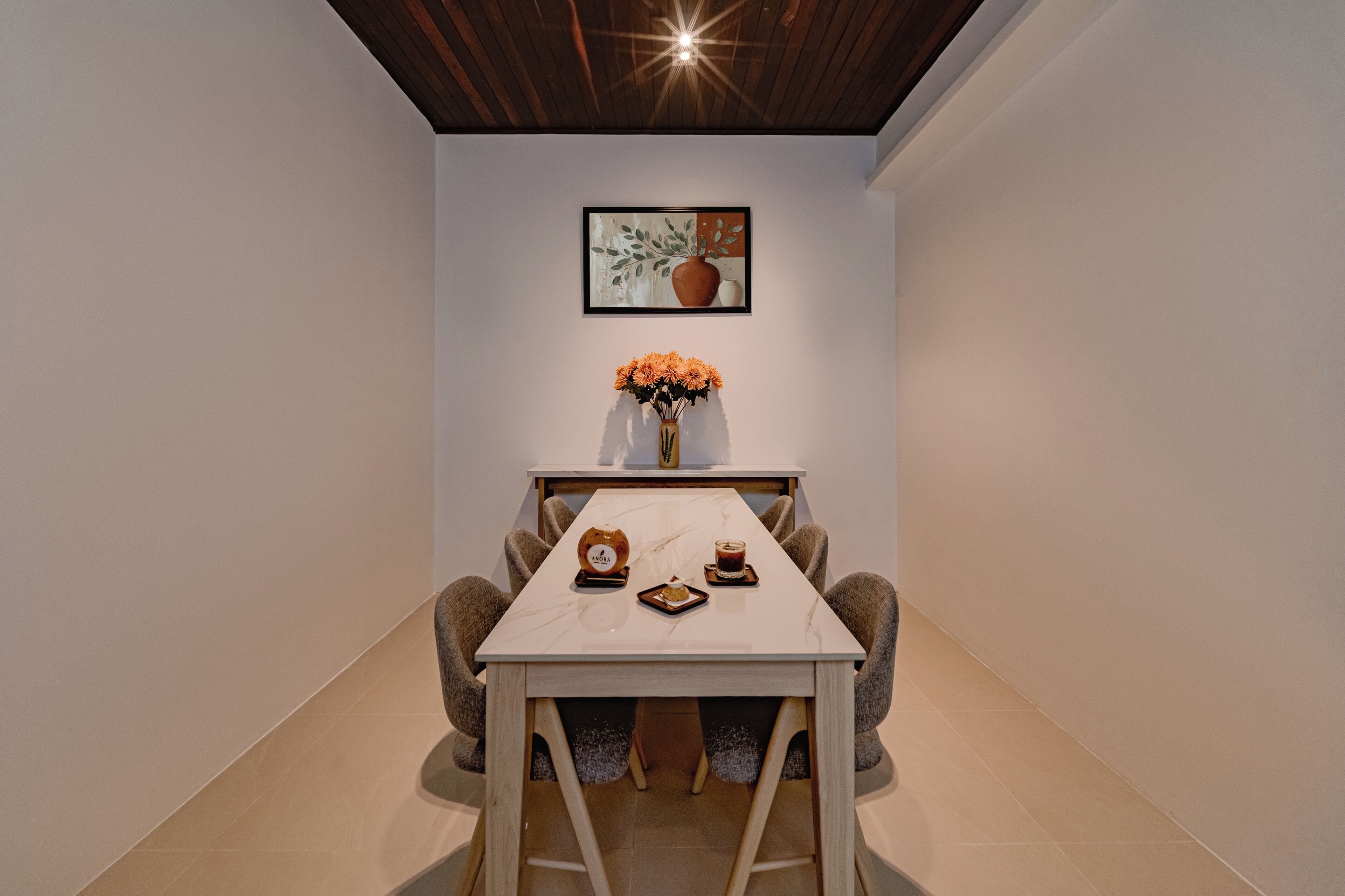Ein Essbereich mit Tisch, Stühlen, einer Blumenvase und einem gerahmten Bild an der Wand.
