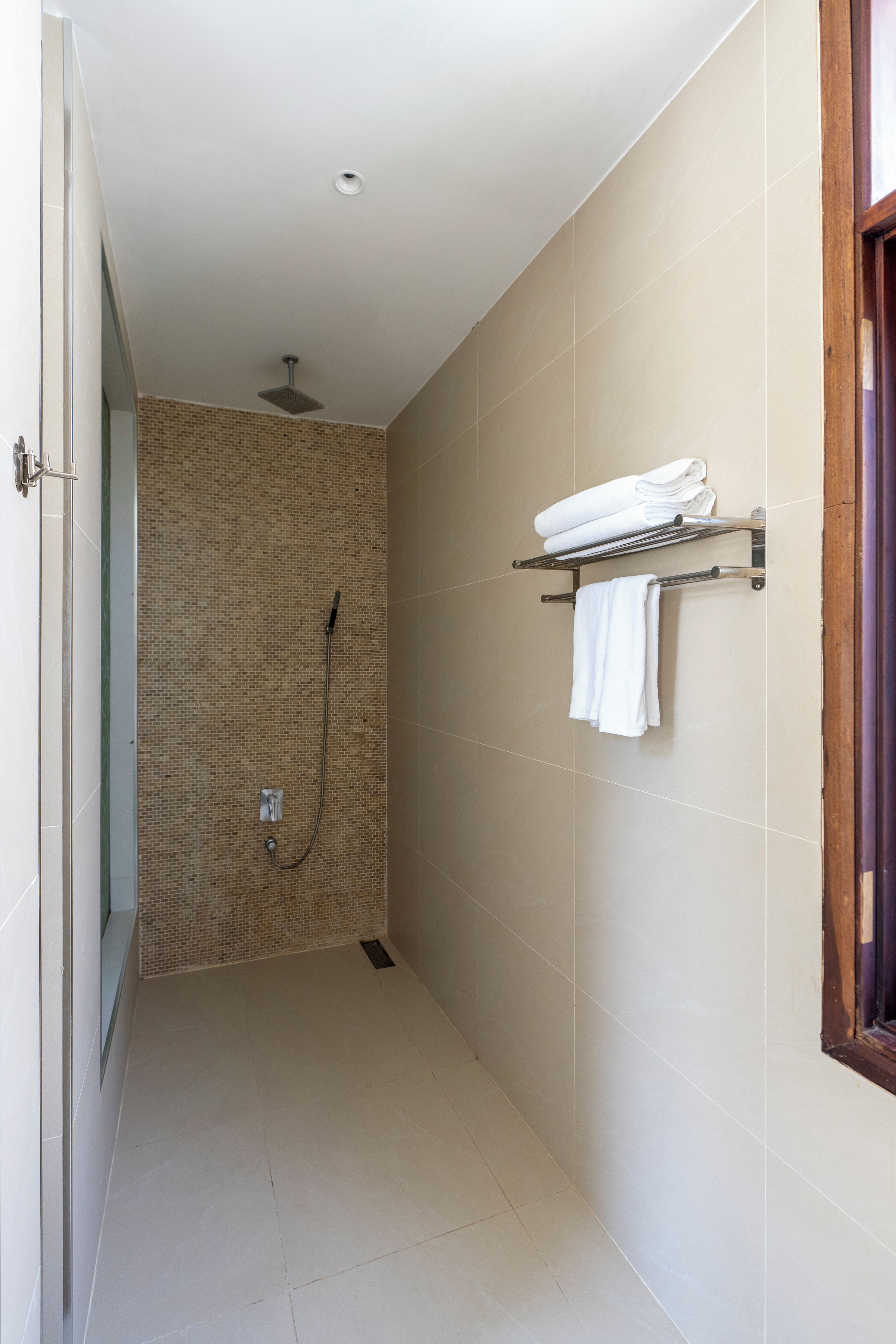 Une salle de bain avec une douche, un porte-serviettes et un sol carrelé.