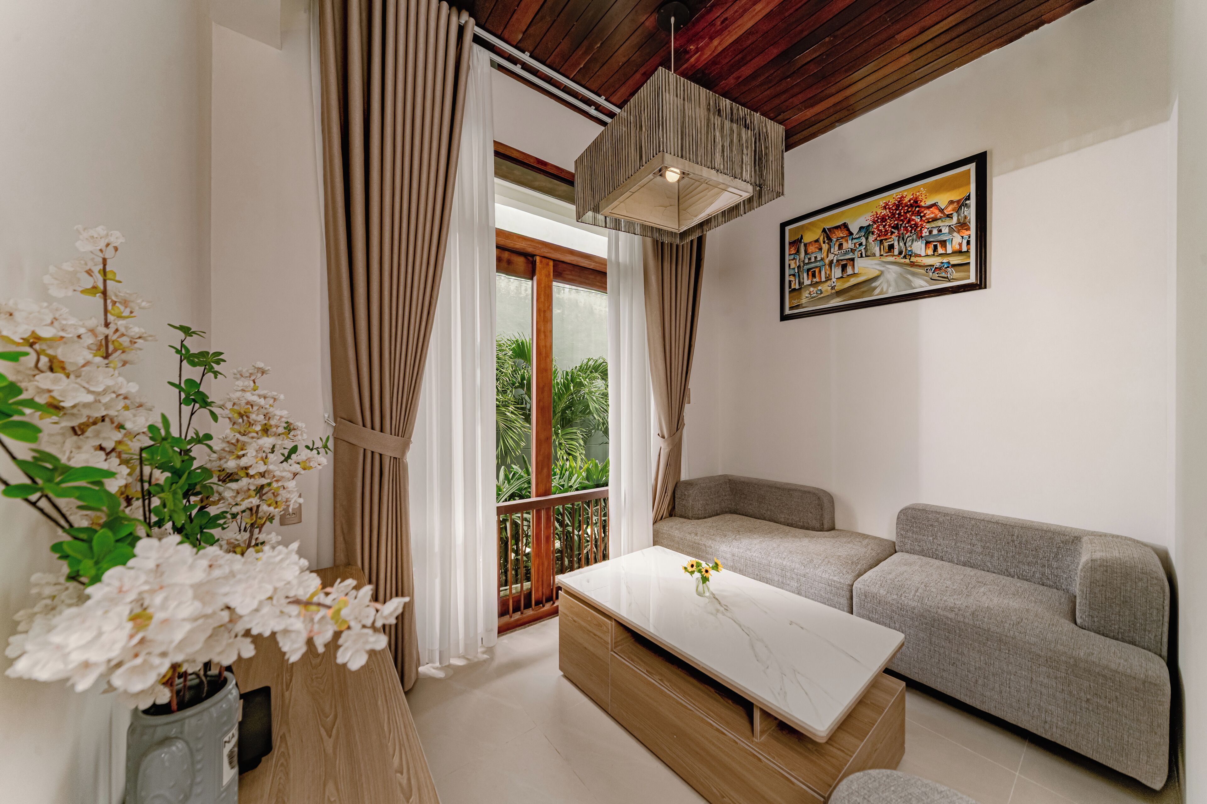 A modern living room with a sofa, a coffee table, a potted plant, and a painting on the wall.
