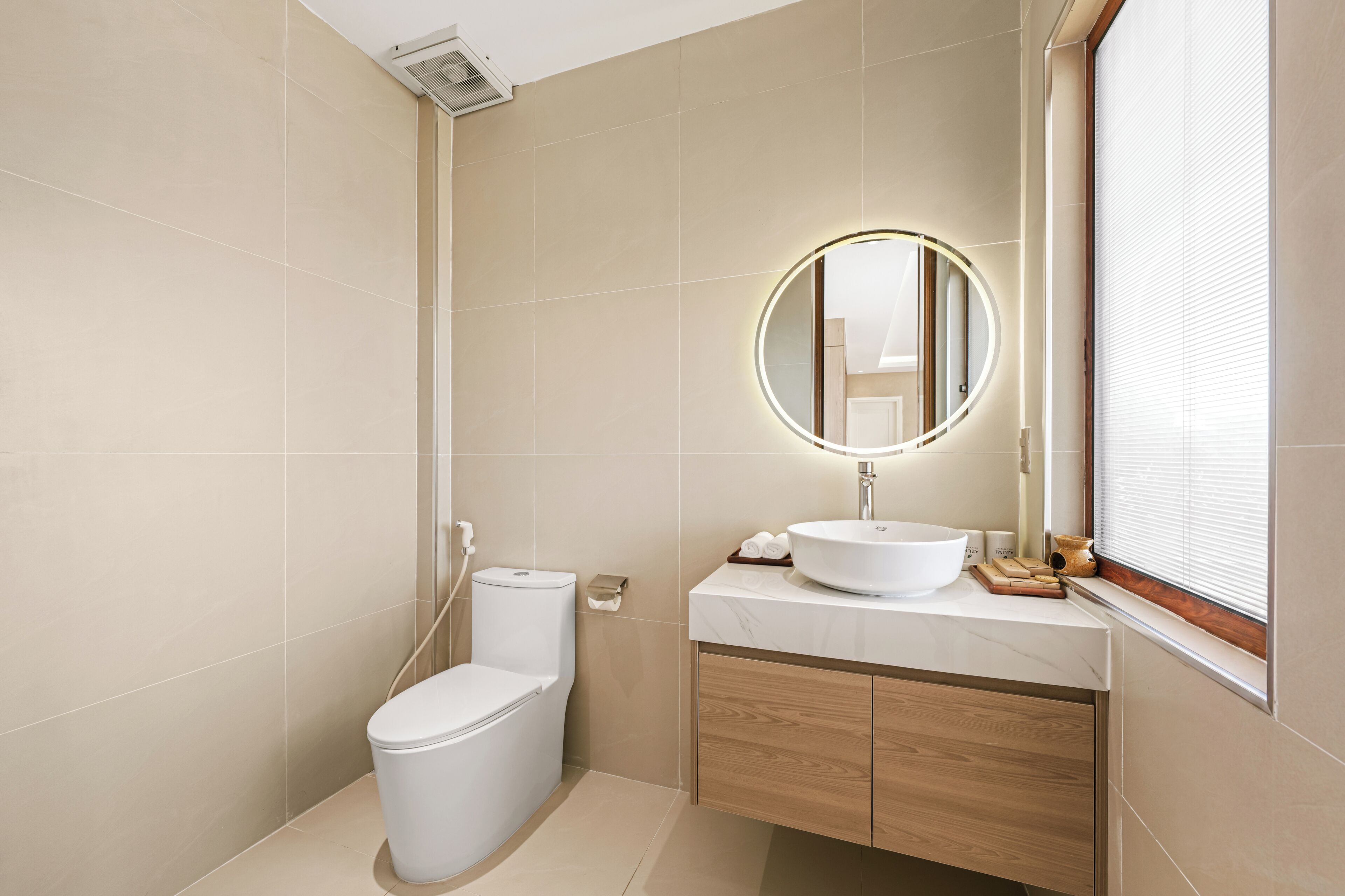 Un baño moderno con inodoro, lavamanos, espejo y ventana.
