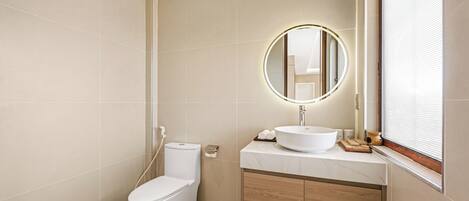 Un baño moderno con inodoro, lavamanos, espejo y ventana.