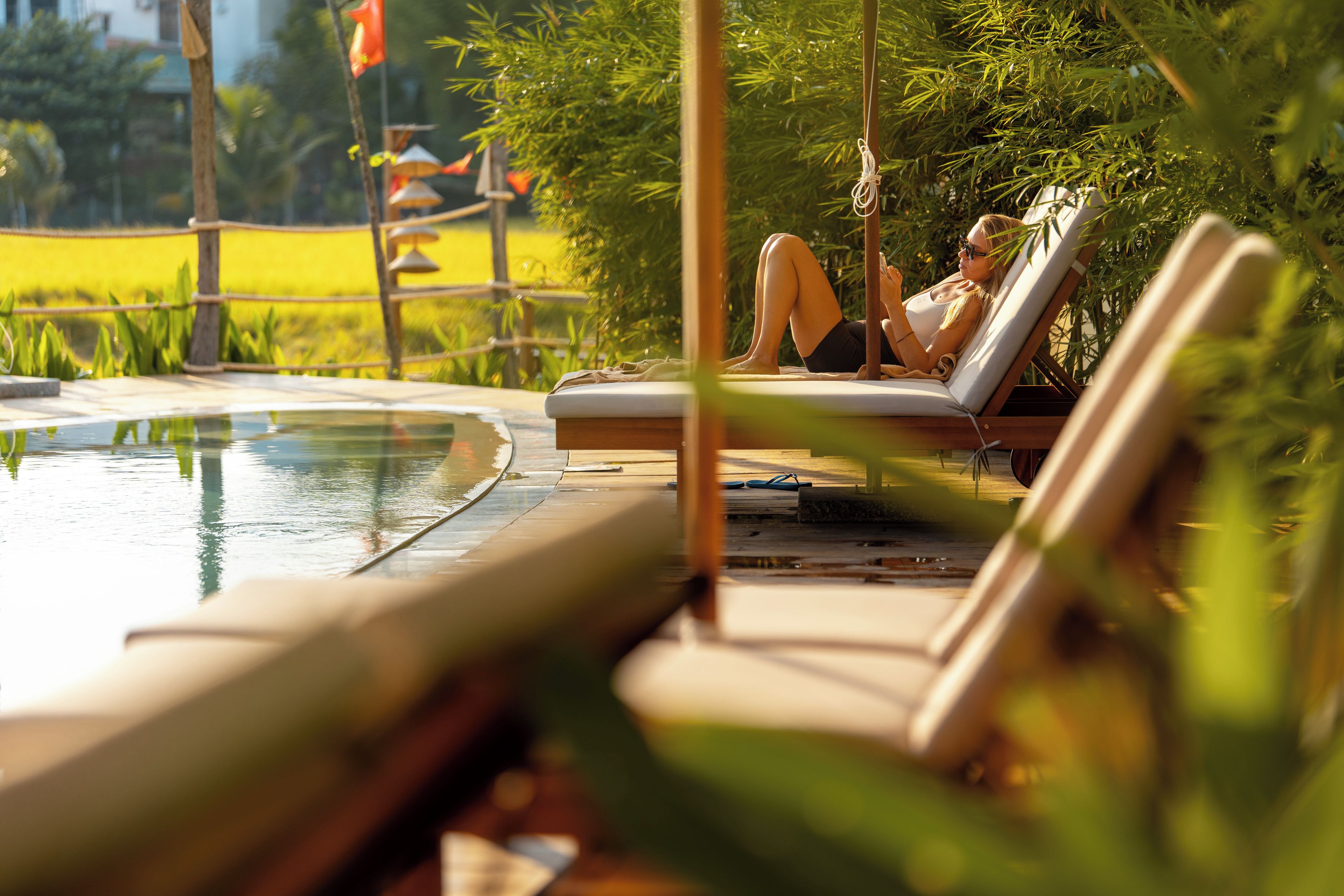 A poolside area with lounge chairs and a person relaxing.