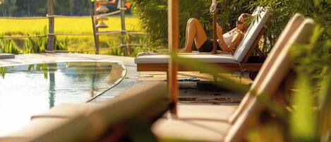 A poolside area with lounge chairs and a person relaxing.