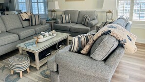 En stue med to grå sofaer, et sofabord og et natbord med en lampe.