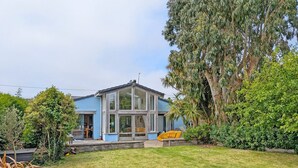 A modern two-story house with a large glass front, a visible deck, and a well-maintained lawn. - Sleeps 8 guests  in 4 bedrooms (Emsworth)