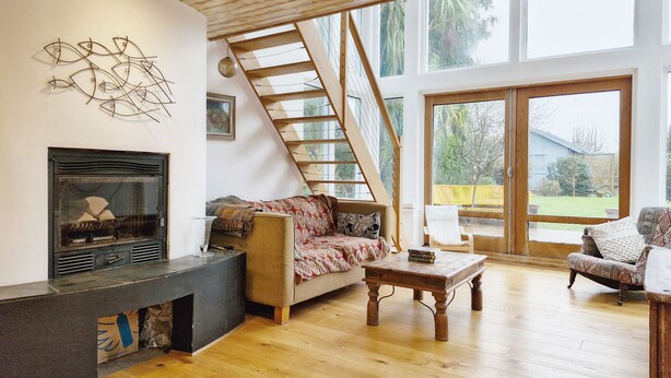 A spacious living area with a fireplace, wooden flooring, a staircase, and large windows. - Sleeps 8 guests  in 4 bedrooms (Emsworth)