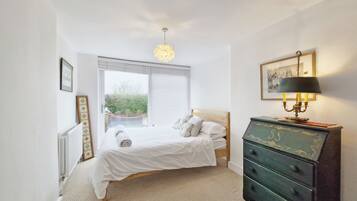 A bedroom with a bed, a dresser, a lamp, and a window.