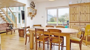 A spacious room with a wooden dining table, chairs, a staircase, and a large window. - Sleeps 8 guests  in 4 bedrooms (Emsworth)