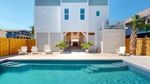 A two-story building with a swimming pool, wooden fence, and outdoor seating. - Salt House | Luxury 7-Suite Beach Retreat w/ Pool & Elevator (Carolina Beach)