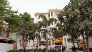 Un hotel con fachada blanca, varios balcones y abundante vegetación.