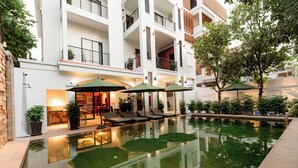 Un edificio moderno con piscina en la azotea, sillones de descanso y sombrillas.